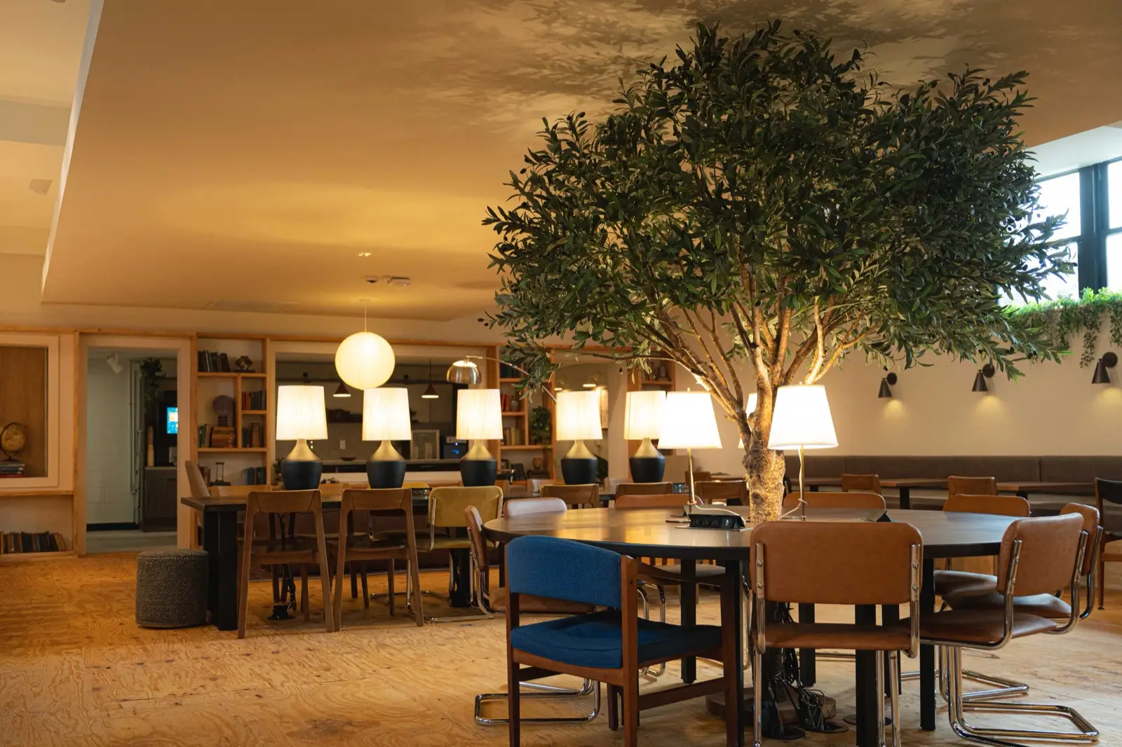 The tree table: a big round table under an indoor tree, lamps glowing, the main floor behind it