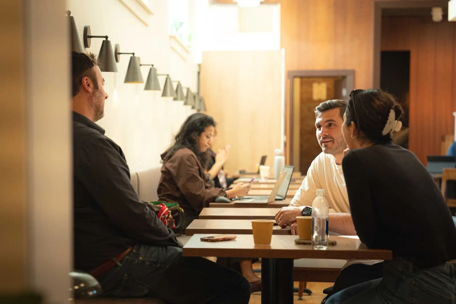 Members talking and working together at a wood table with coffee cups